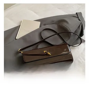 Detailed view of dark brown patent leather handbag with a golden twist metal clasp