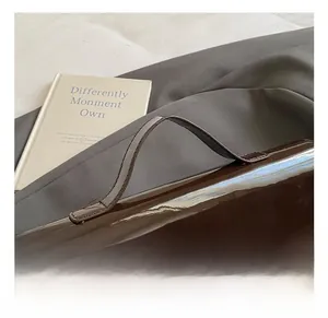 Detail shot of the glossy patent leather handle and golden hardware on the dark brown bag