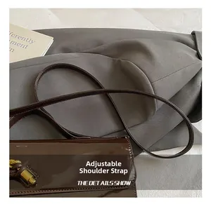 Detail of adjustable shoulder strap and metal hardware on dark brown patent leather bag