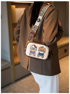Close-up of cute cartoon cat prints on a white crossbody bag with wide shoulder strap