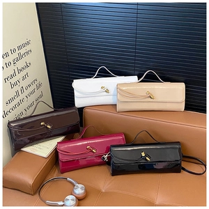 Detailed display of glossy patent leather handbags in five colors on a leather sofa