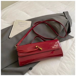 Top view of a glossy burgundy leather handbag with gold twist lock on fabric
