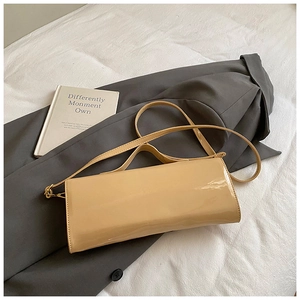Close-up of minimalist glossy nude patent leather baguette bag on white fabric background