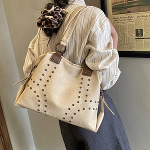 Large beige tote bag with rivets and brown leather straps for daily commute use