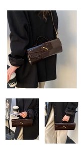 Detail of dark brown patent leather handbag with golden twist lock and shoulder strap