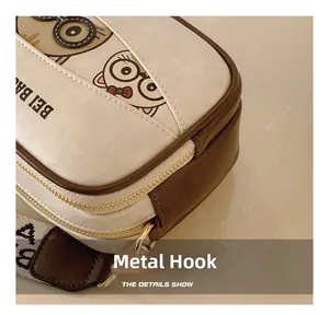 Detail showing the light gold metal hook and woven shoulder strap on a cartoon box bag