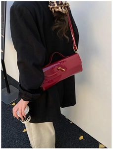 Detail of red glossy patent leather crossbody bag with a golden metal twist lock