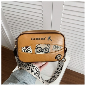 Close-up of cute cartoon cat prints and wide brand strap on a brown PU leather box bag
