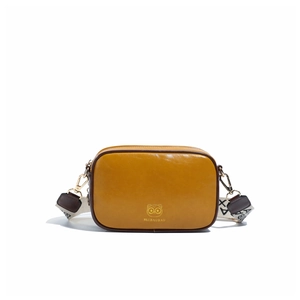 Detail of yellow camera bag with golden cat logo and stylish black white woven strap
