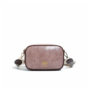 Detailed view of dusty pink oil wax leather crossbody bag with golden owl emblem and strap
