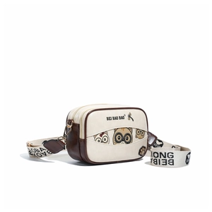 Close-up of cute cartoon cat print and wide branded strap on cream crossbody bag