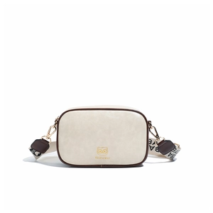 Detailed shot of beige crossbody box bag with golden cat logo and wide woven strap