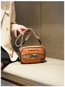 Close-up of yellow cartoon cat crossbody bag with wide jacquard strap on a model