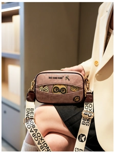 Detail of cute cat illustration and logo on pink crossbody bag with wide strap