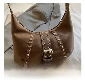 Dettaglio di rivetti argentati e fibbia in metallo sulla borsa hobo in camoscio marrone