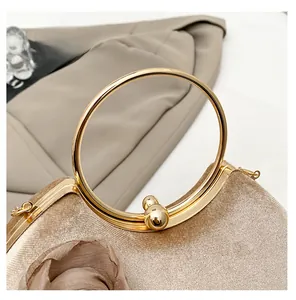 Detail eines runden Metallgriffs und Doppelperlenverschlusses an der Abendtasche