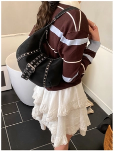 Borsa hobo nera con borchie indossata dalla modella, stile vintage Y2K e forma a mezzaluna