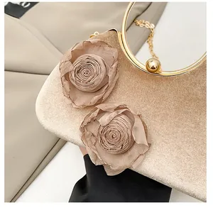 Detail der champagnergoldenen Abendtasche mit 3D-Stoffrose und Metallgriff