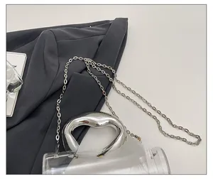 Detail of transparent acrylic cylinder bag with silver handle and metallic chain strap
