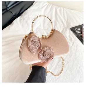 Detail einer Champagner-Samtabendtasche mit 3D-Rosenblüten und goldenem Rundgriff