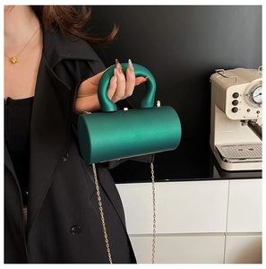 Detail of emerald green acrylic cylinder bag with gold chain and circular handle
