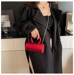 Close-up of deep red cylindrical barrel bag with satin finish and golden chain strap