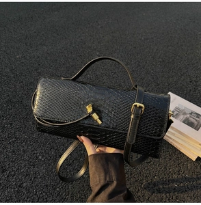 Close-up of black snakeskin texture leather bag with elegant gold metal twist lock