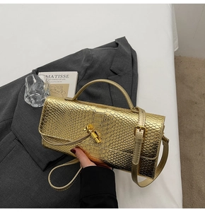 Detail of gold faux crocodile embossed pattern and knot clasp on luxury clutch bag