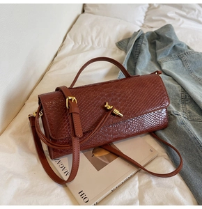 Macro shot of brown crocodile-embossed leather with a gold knotted clasp on a clutch bag
