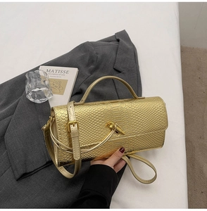 Detail of gold snake pattern texture on evening clutch bag with turn-lock metal buckle