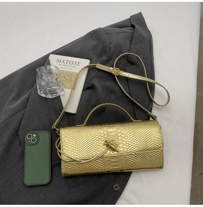 Detail of gold snake pattern handbag with metallic finish on dark grey blazer