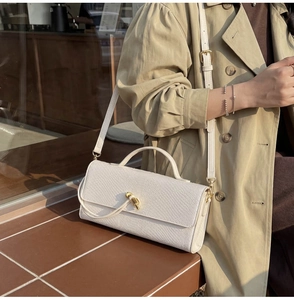 Detail of white snakeskin texture leather bag with elegant gold twisted metal buckle