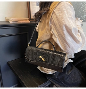Detail of black snake pattern handbag with gold twist lock in a vintage setting