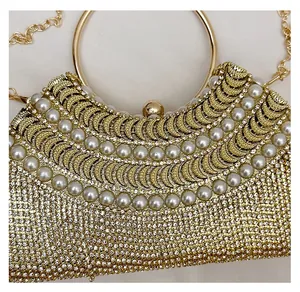 Close-up of gold evening clutch featuring faux pearls, rhinestones and metal ring handle