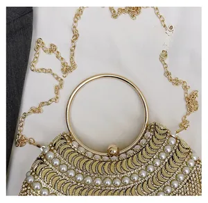 Detailed shot of golden half-moon evening bag with bead embroidery and faux pearls