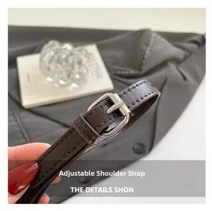 Detail of adjustable dark brown leather shoulder strap with silver buckle and stitching