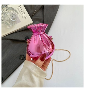 Nahaufnahme der rosa Metallic-Glückstasche mit Goldkette auf minimalistischem Grund