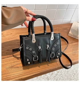 Detail of black punk style handbag with metallic rivets and woven texture handle