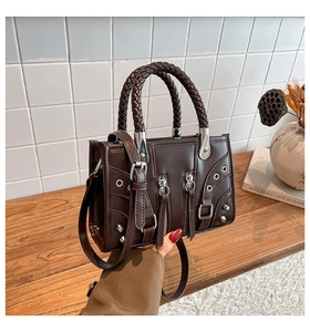 Detail of dark brown leather motorcycle bag with silver rivets and woven handle