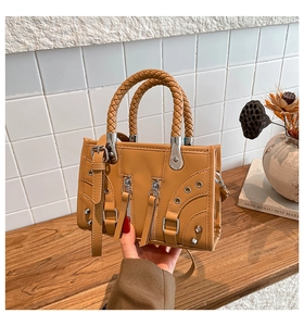 Detailed view of brown motorcycle style mini handbag with woven handles and silver studs