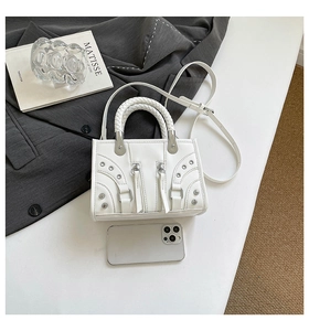 Detailed view of a white studded mini crossbody bag with woven handles and silver hardware