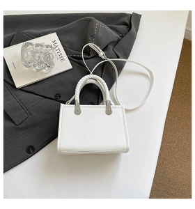 Detail of white leather handbag featuring woven handle and silver metal hardware accents