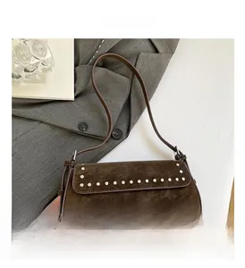 Detail of dark brown suede shoulder bag with silver rivet studs on a grey blazer
