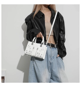 Detail of white biker style bag with silver rivets and unique woven handle