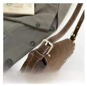 Detail of dark brown leather bag with silver rivets and adjustable buckle strap