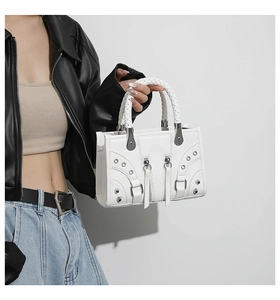 Detail of white leather motorcycle handbag with woven handles and silver metallic hardware