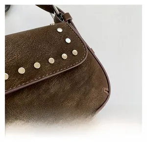 Close-up detail of silver metal rivets on dark brown suede retro underarm shoulder bag