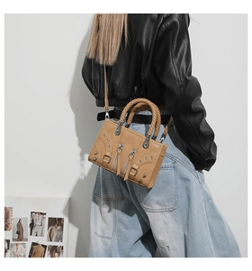 Detail of camel motorcycle bag featuring woven handles, metal rivets, and adjustable strap