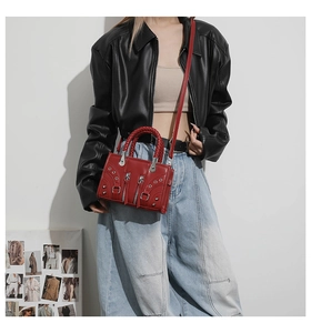 Detail of red motorcycle style handbag with silver rivets and studs on biker jacket
