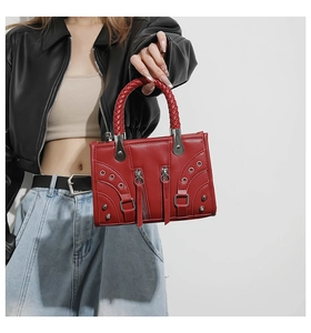 Detail of red punk rivets handbag featuring woven leather handles and silver metal studs